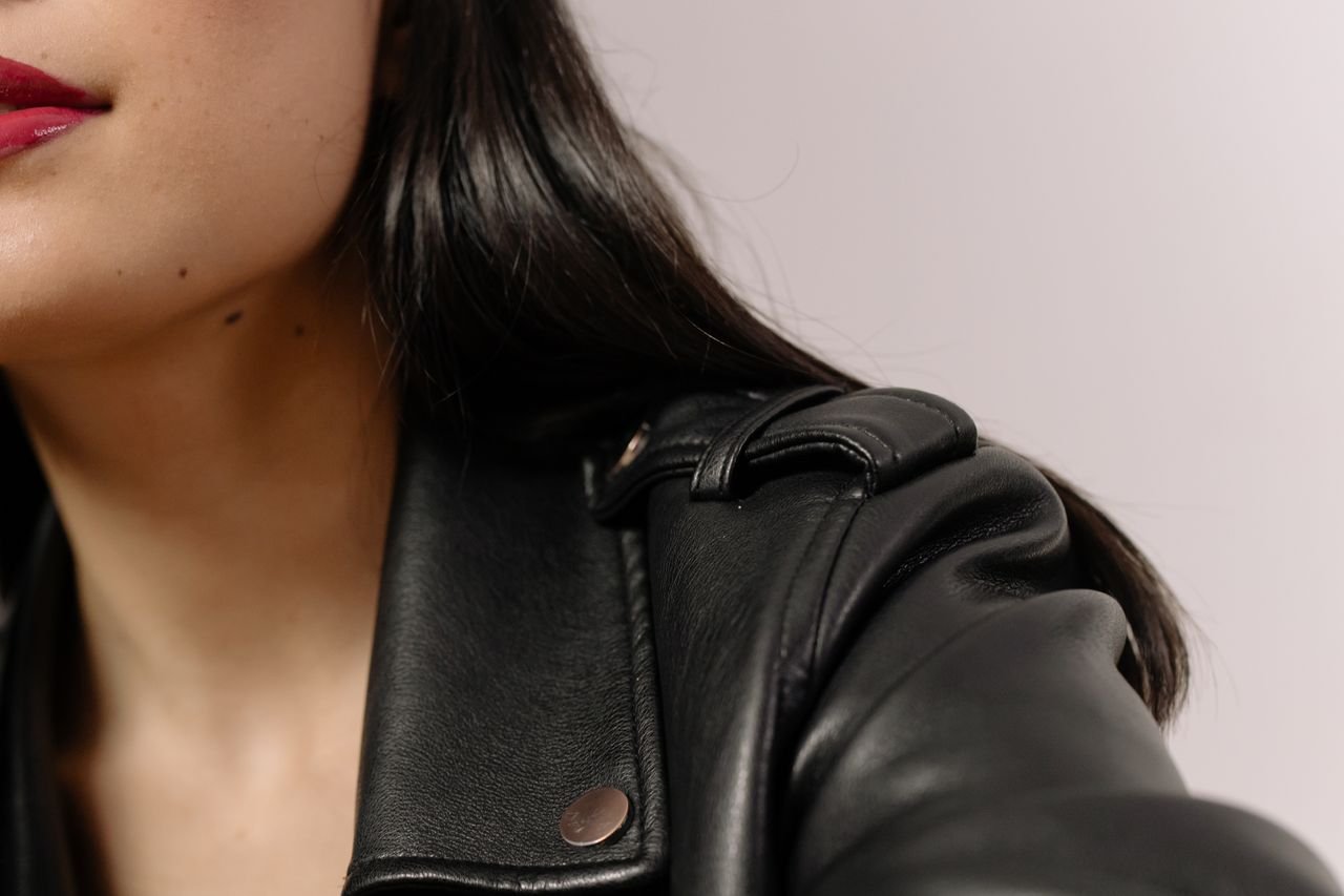 Detailed close-up of a woman with red lipstick and black leather jacket, showcasing style and elegance.