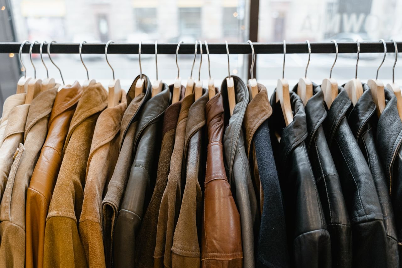 A collection of leather and suede jackets hanging on a clothes rack in a stylish boutique.